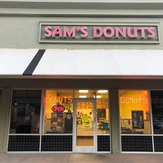 The Sam's Donuts storefront on Snell Ave with a pink illuminated sign and DONUTS neon in the windows.