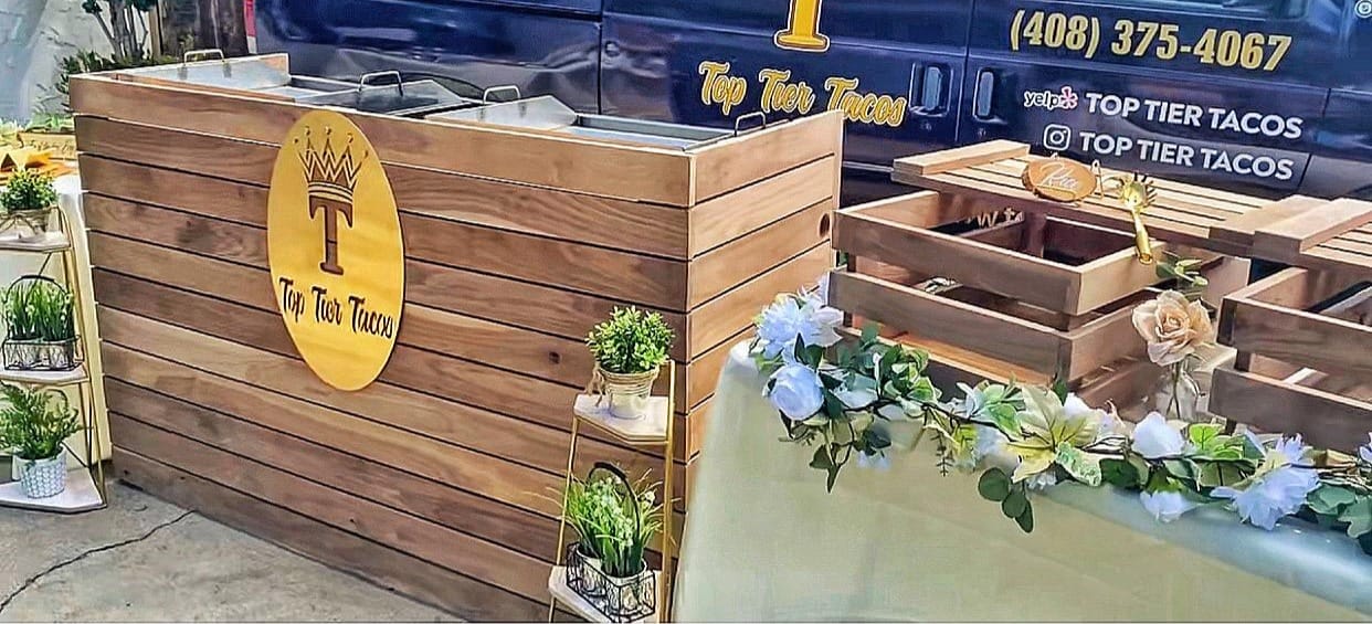 Top Tier Tacos branded wooden taco bar with gold logo, floral arrangements, and elegant table setup